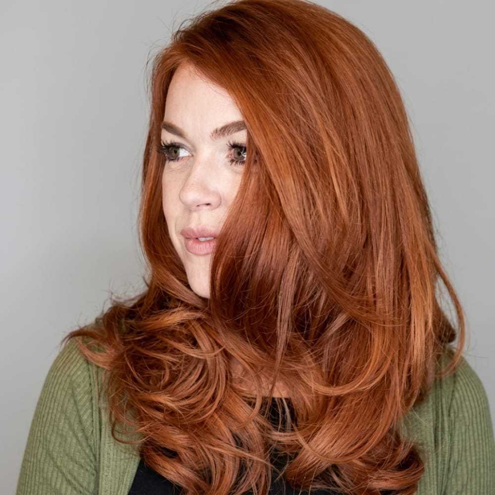 ```plaintext
Person with long red hair gazing to the side, wearing a green cardigan.
```