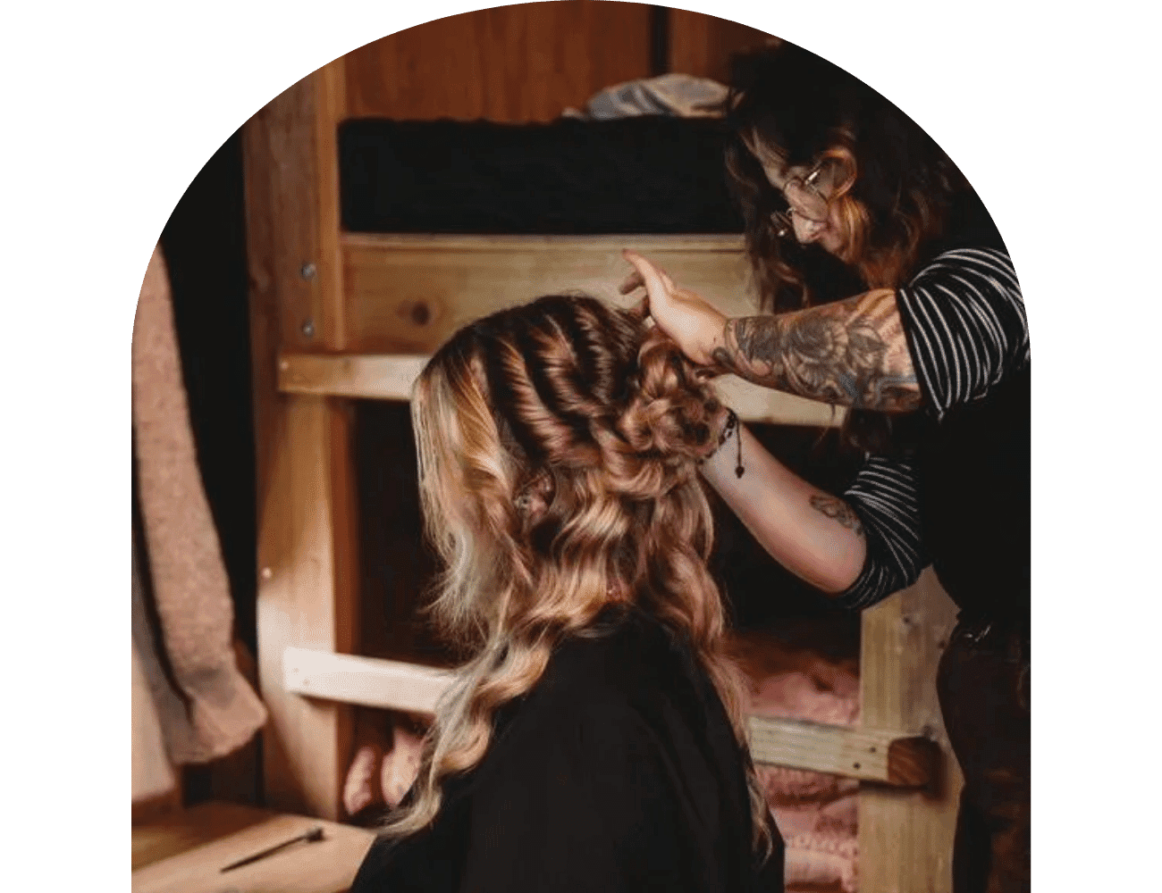 Hairstylist crafting intricate curls in a cozy, wood-furnished room.